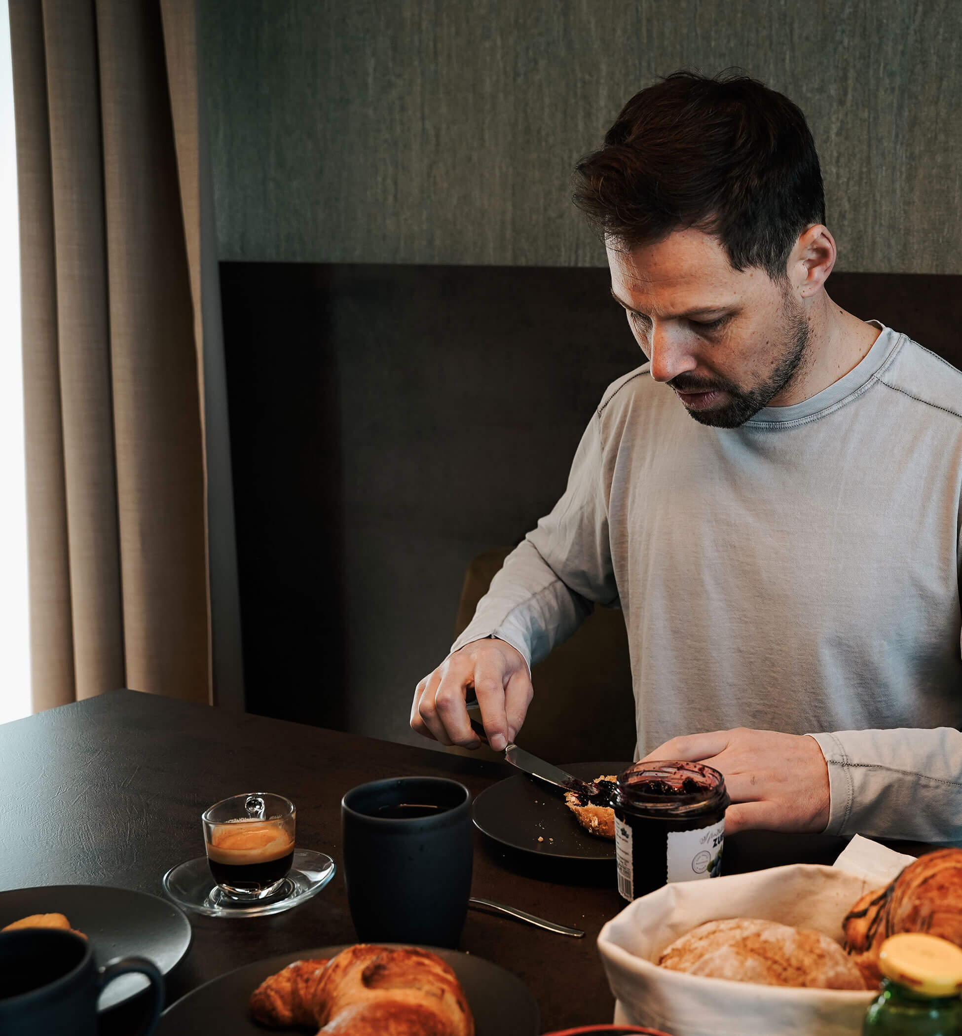 A man sits at the breakfast table and spreads a jam sandwich - PustraBase