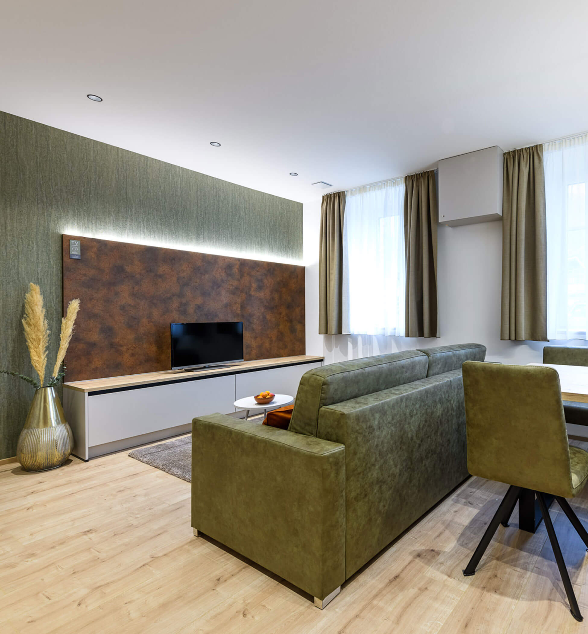 Living room with green sofa in Villa Fauster Apartment Linda - PustraBase